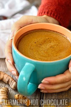 a person holding a cup of coffee with ginger on the table next to some sliced ginger