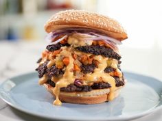 a cheeseburger with onions, lettuce and other toppings on a blue plate