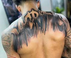 the back of a man with tattoos on his upper and lower part of his body