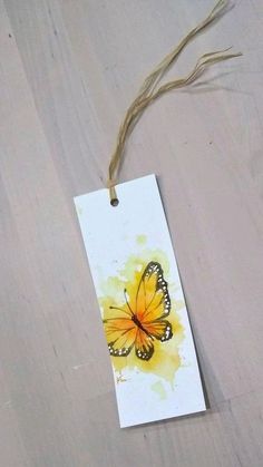 a tag with a yellow butterfly painted on it hanging from a string attached to a wall