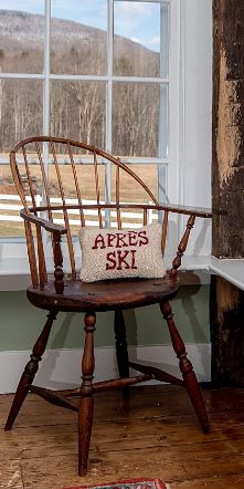 a wooden chair sitting in front of a window with a pillow on top of it