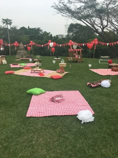 an outdoor picnic is set up in the grass with red and white decorations on it