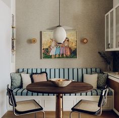 a dining room table with two chairs and a painting on the wall