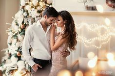 a man and woman standing in front of a christmas tree