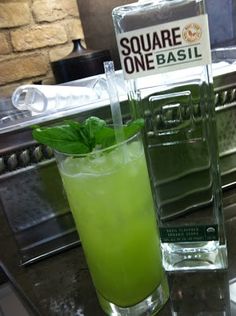 two glasses filled with green liquid sitting on top of a counter next to each other