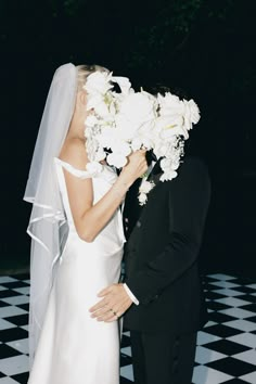 a bride and groom kissing in front of a black and white checkered floor