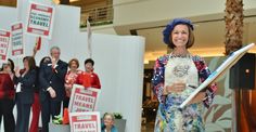 a woman standing in front of a group of people holding signs