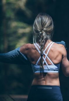 a woman with her back turned to the camera, wearing black sports bra and blue leggings