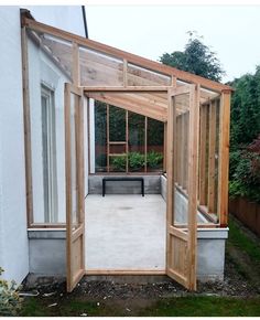 an open door leading into a small garden area with plants in the back ground and a bench on the other side