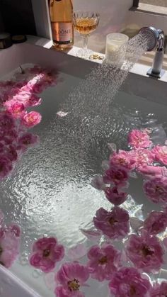 pink flowers are floating in a bathtub with water running down the side and on the floor