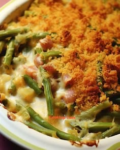 a casserole dish with green beans, ham and gravy on top