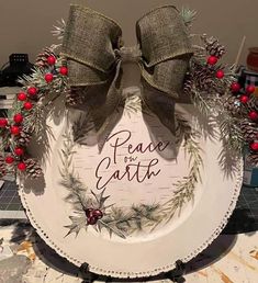 a plate decorated with pine cones and red berries is sitting on a counter top that says peace & gaithe