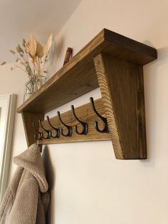 a coat rack with hooks and clothes hanging on the wall next to a towel rack