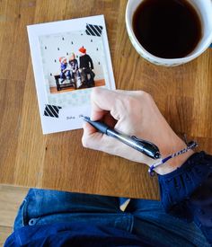 a person sitting at a table with a pen in their hand and a photo on the table