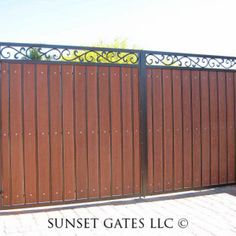 an iron gate with wooden panels and wrought bars on the top, in front of a brick