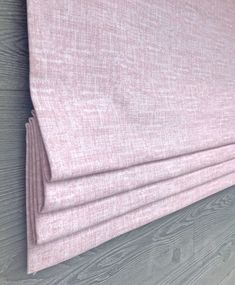 a close up of a pink curtain on a wooden wall with grey wood flooring