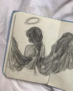 an open notebook with a drawing of two angel's wings on top of it