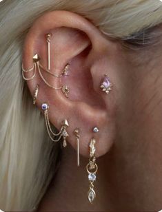 a woman wearing ear piercings with different types of jewelry on her ears and behind the ear