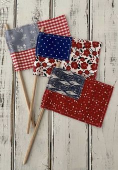 three red, white and blue patchwork coasters with wooden sticks sticking out of them