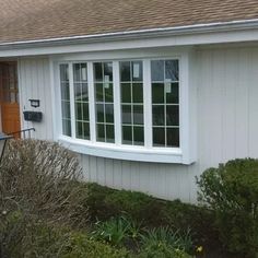 a small white house with an orange front door and window on the side of it