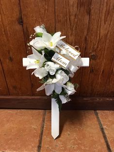 a bridal bouquet with white lilies and chocolate bar on it sitting against a wooden wall