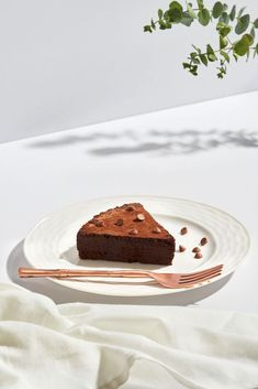 a piece of chocolate cake sitting on top of a white plate next to a fork