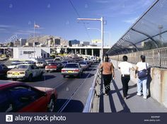 two men walking down the side of a bridge with cars on it