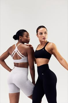 two women standing next to each other in sports bra tops and leggings, one wearing