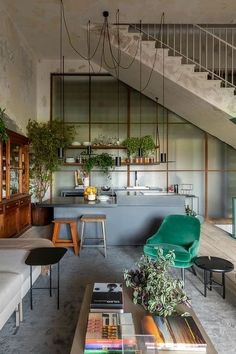 a living room filled with furniture and lots of plants on top of the shelves next to a stair case