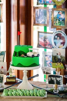 a green cake sitting on top of a wooden table next to pictures and other items