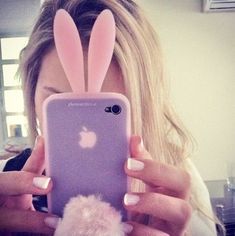 a woman taking a selfie with her phone and bunny ears sticking out of it