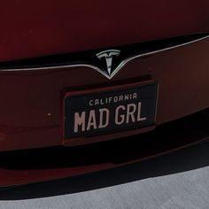 the back end of a red car with a license plate that says mad girl on it