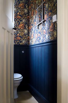 a bathroom with blue walls and floral wallpaper on the walls, along with a white toilet