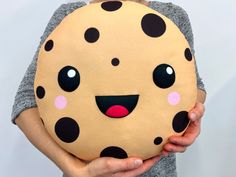 a person holding a pillow with polka dots on it and a face painted on the front