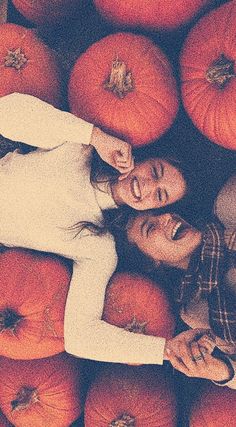 two people standing in front of a pile of pumpkins