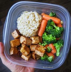 a plastic container filled with rice, broccoli and carrots