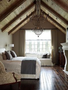 a bedroom with wood flooring and a chandelier hanging from the vaulted ceiling