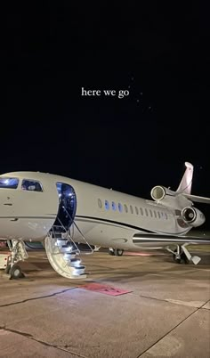 an airplane is parked on the tarmac at night with a message written above it that reads, here we go