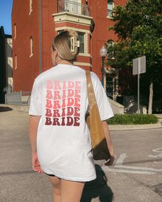 a woman walking down the street wearing a bride t - shirt