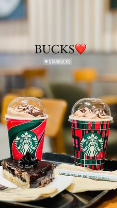 two cups of starbucks coffee sit next to each other on a tray in a restaurant