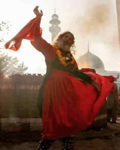 a man dressed in red and green is dancing with his hands up to the sky