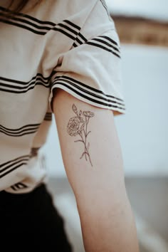 a woman's arm with a small flower tattoo on the left side of her arm