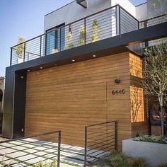 two people are sitting at a table in front of a modern house with wood siding and metal railings