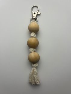 three wooden beads with tassels are hanging from a metal hook on a gray background