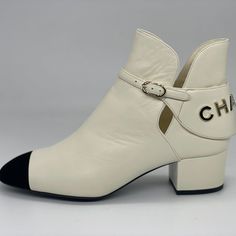 Chanel 2021 (21a Season) Ivory Lambskin Leather Booties Have A Black Velvet Cap Toe And A Goldtone Chanel Signature On The Back. Chanel Embossed Buckle. 1.5" Leather Covered Block Heel. Padded Leather Insole. Leather Sole. Shaft: 4.5". Made In Italy. Designer Color: Ivory/Black. Size: 37 Eu (Insole Measures Approx. 9.5".) Typically Chanel Shoes Run Small. Brand New With The Box And A Dust Bag. Chic White Closed Toe Heeled Boots, Luxury Boots With Branded Heel Counter For Spring, Luxury Medium Width Boots For Spring, White Leather Booties For Fall, Chic White Booties, Cream Round Toe Heeled Boots In Calf Leather, Cream Calf Leather Heeled Boots With Round Toe, White Calf Leather Boots With Round Toe, White Ankle Boots With Contrasting Heel Counter