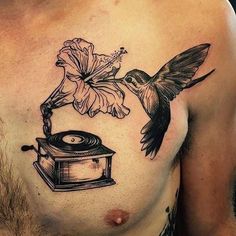 a man with a tattoo on his chest has a hummingbird flying over a record and flower