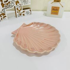 a pink scallop shaped dish sitting on top of a table next to boxes