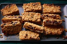 several squares of food are on a black platter with nuts and raisins