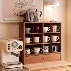 a coffee machine sitting on top of a wooden table next to a shelf filled with cups