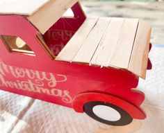 a wooden toy truck sitting on top of a bed